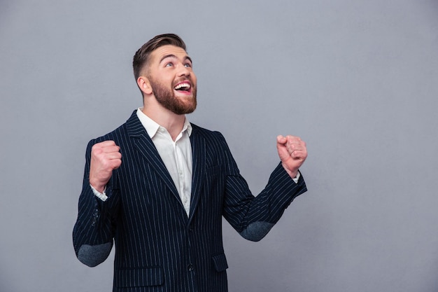 Ritratto di un uomo d'affari felice che celebra il suo successo sul muro grigio