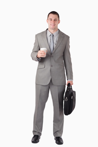 Ritratto di un uomo d&#39;affari in possesso di una tazza di caffè e una borsa del computer contro uno sfondo bianco