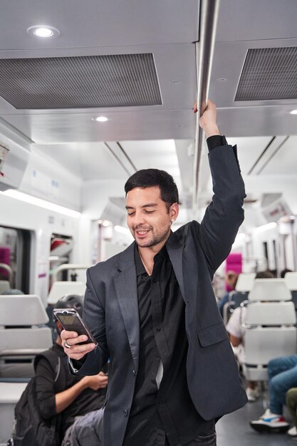 ritratto di un uomo d'affari latino che guarda il suo smartphone mentre viaggia su un treno o una metropolitana