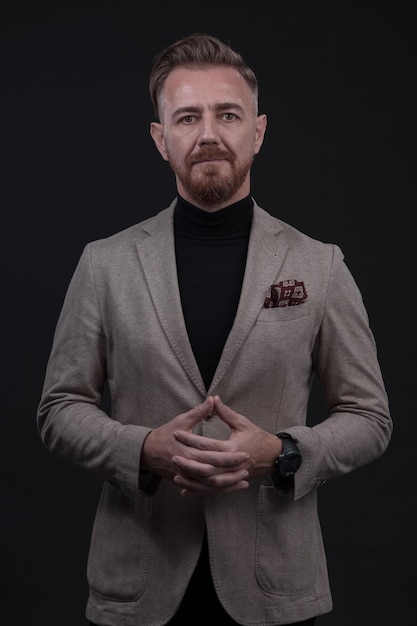 Ritratto di un uomo d'affari senior elegante ed elegante con la barba e abiti da lavoro casual in studio fotografico isolato su sfondo scuro che gesturing con le mani. Foto di alta qualità