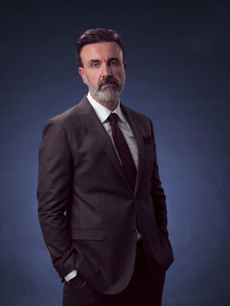 Ritratto di un uomo d'affari senior elegante ed elegante con la barba e abiti da lavoro casual in studio fotografico isolato su sfondo scuro che gesturing con le mani. Foto di alta qualità
