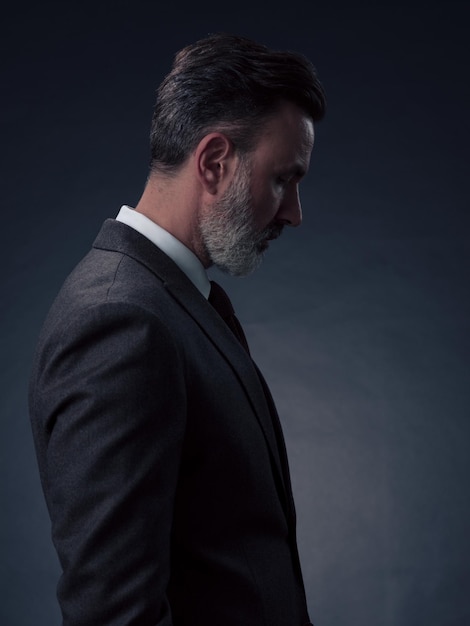 Ritratto di un uomo d'affari senior elegante ed elegante con la barba e abiti da lavoro casual in studio fotografico isolato su sfondo scuro che gesturing con le mani. Foto di alta qualità