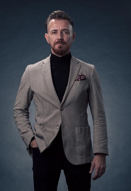 Ritratto di un uomo d'affari senior elegante ed elegante con la barba e abiti da lavoro casual in studio fotografico isolato su sfondo scuro che gesturing con le mani. Foto di alta qualità