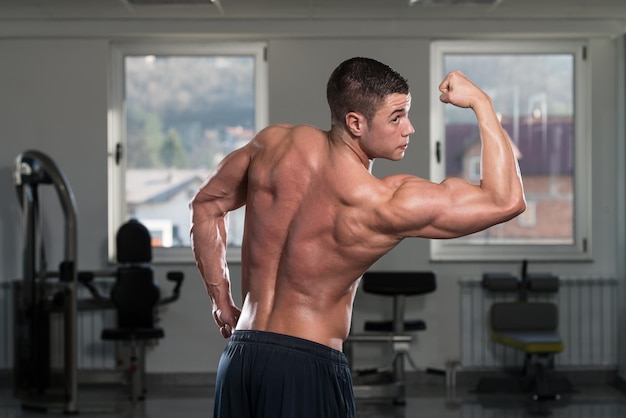 Ritratto di un uomo fisicamente in forma che mostra il suo corpo ben allenato in palestra
