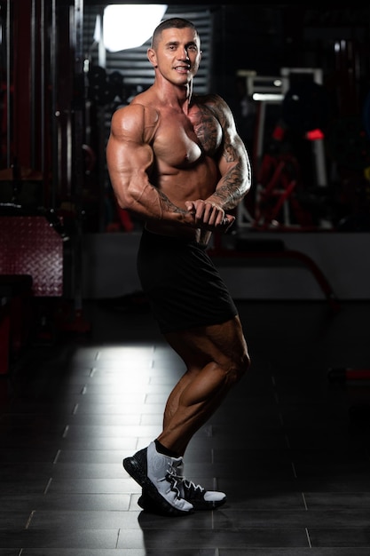 Ritratto di un uomo fisicamente in forma che mostra il suo corpo ben allenato modello di fitness bodybuilder atletico muscolare in posa dopo gli esercizi