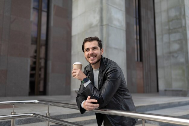 Ritratto di un uomo forte con una tazza di caffè sorridente guardando la telecamera fuori dall'ufficio