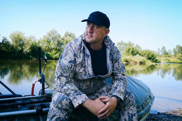 Ritratto di un uomo in vacanza nella natura in sella a un airboat sul fiume in abiti da cacciatore