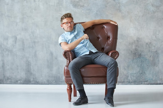 Ritratto di un uomo intelligente alla moda fissa nella fotocamera piccola camicia blu carismatica con la barba lunga s