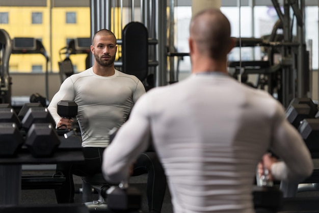 Ritratto di un uomo muscoloso che riposa sulla panchina in palestra