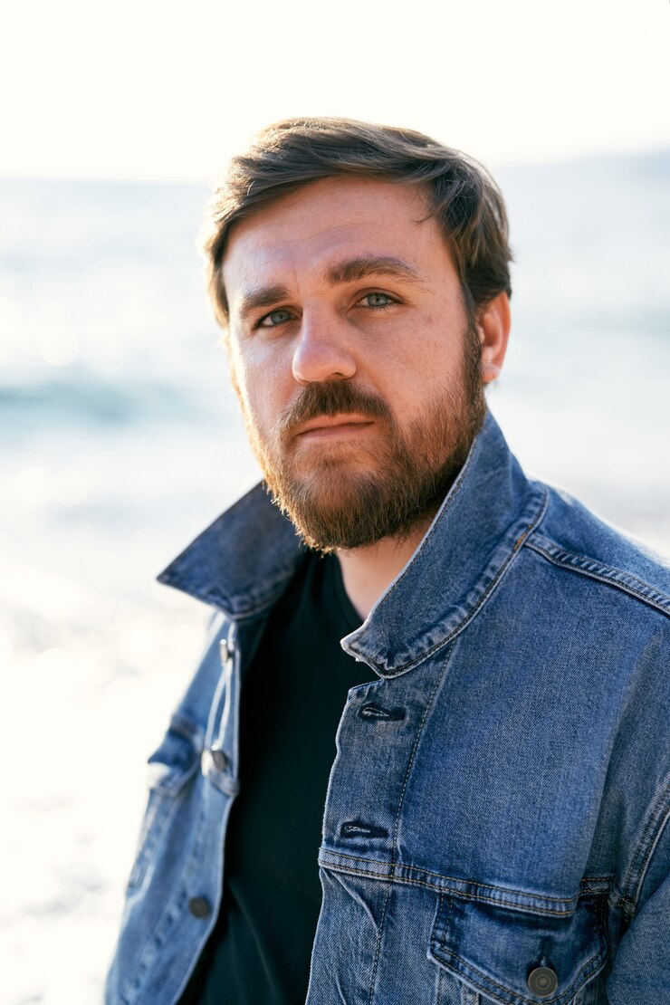 Foto ritratto di un uomo pensieroso in una giacca di jeans sullo sfondo del primo piano del mare