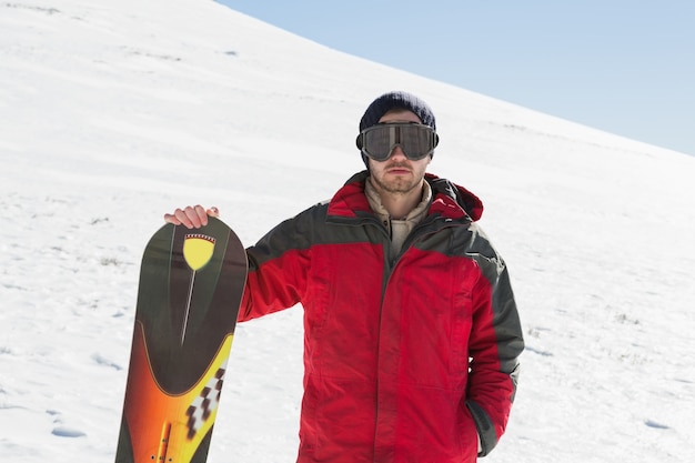 Ritratto di un uomo serio con tavola da sci in piedi sulla neve