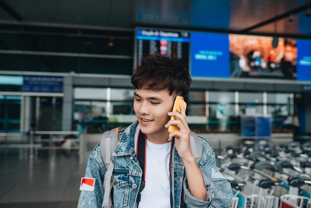 Ritratto di un uomo sorridente che manda messaggi mentre aspetta un taxi in aeroporto