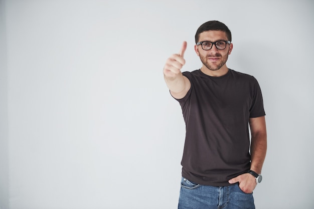 Ritratto di un uomo sorridente in bicchieri che mostra il pollice in su su sfondo bianco.