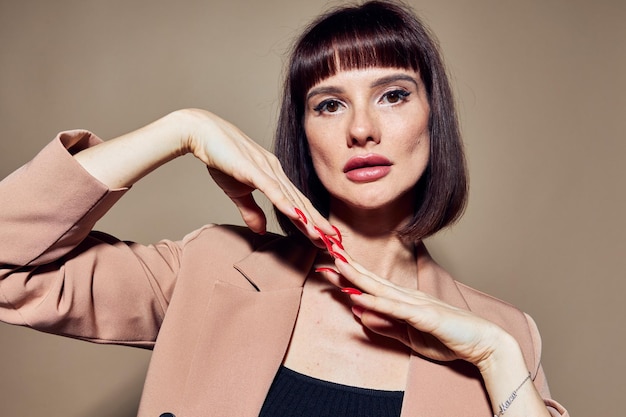 Ritratto di un vestito dai capelli corti della donna che gesturing con le mani ha isolato lo sfondo