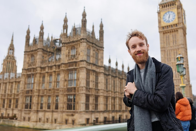 Ritratto di un viaggiatore maschio barbuto con uno zaino sullo sfondo del Big Ben a Londra