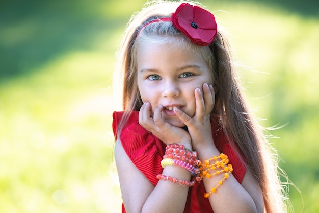 Ritratto di una bambina abbastanza alla moda in abito rosso che si gode una calda giornata estiva di sole.