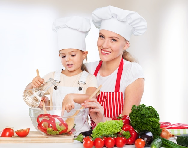 Ritratto di una bambina adorabile e di sua madre che cucinano insieme