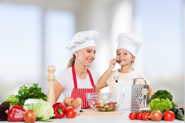 Ritratto di una bambina adorabile e di sua madre che cucinano insieme