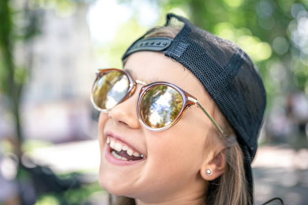 Ritratto di una bambina alla moda in occhiali da sole all'aperto.