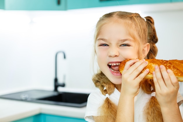 Ritratto di una bambina bionda che morde una baguette fresca