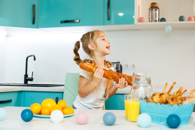 Ritratto di una bambina bionda che morde una baguette fresca