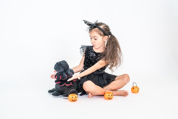 ritratto di una bambina bruna con un cappello nero e un vestito nero nelle decorazioni di Halloween.