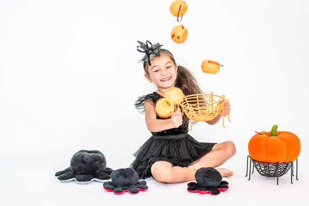 ritratto di una bambina bruna con un cappello nero e un vestito nero nelle decorazioni di Halloween.