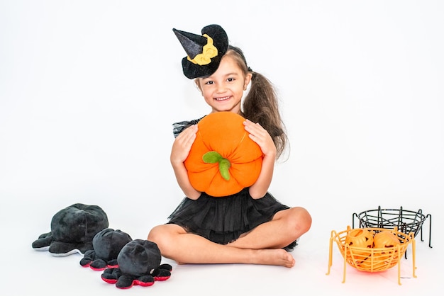 ritratto di una bambina bruna con un cappello nero e un vestito nero nelle decorazioni di Halloween.
