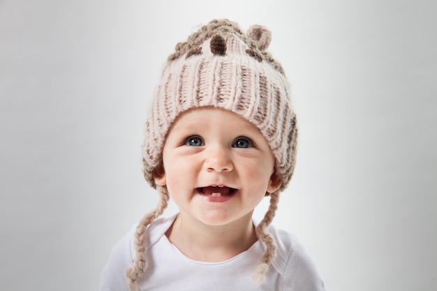 Ritratto di una bambina carina in un enorme cappello lavorato a maglia marrone. Isolato su sfondo bianco.