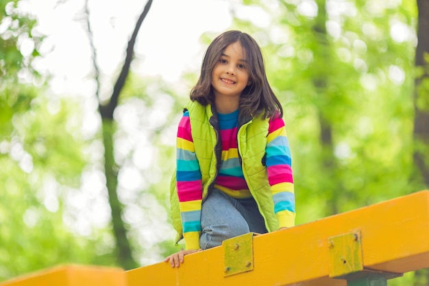 Ritratto di una bambina carina su una piattaforma di legno luminosa nel parco in primavera