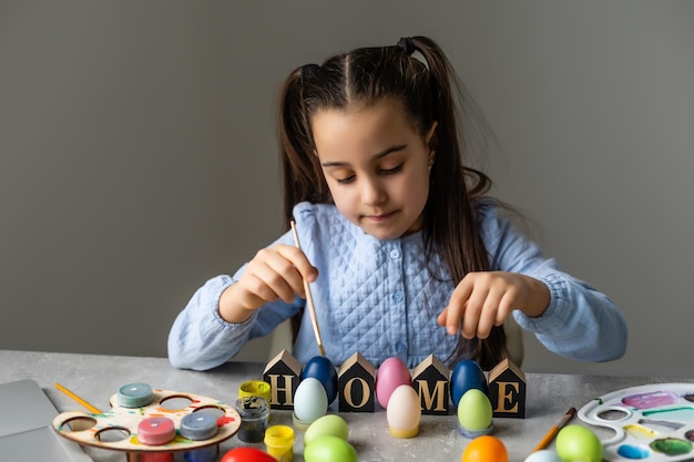 Ritratto di una bambina carina vestita con orecchie da coniglio pasquale che tengono uova colorate.