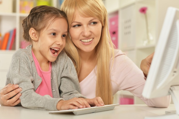 Ritratto di una bambina che gioca con la madre al computer a casa