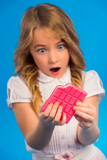 Ritratto di una bambina che mangia cioccolato rosa.