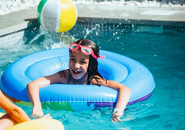 Ritratto di una bambina che si diverte in una piscina con un galleggiante. Concetto divertente.