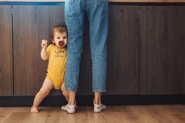 Ritratto di una bambina che tiene le gambe delle madri a casa per la cura del bambino