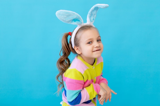 Ritratto di una bambina con orecchie di coniglio in una giacca a righe Il concetto di vacanza di Pasqua Studio fotografico di sfondo blu posto per il testo