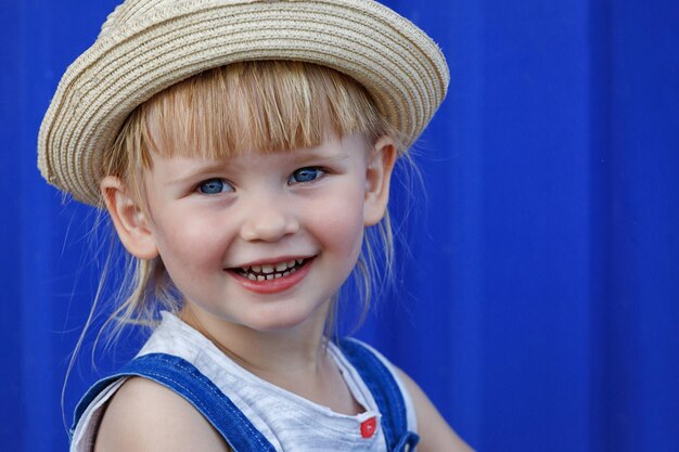 Ritratto di una bambina con un cappello di paglia Guarda lo spettatore e sorride alla telecamera