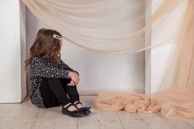 Ritratto di una bambina di 5-6 anni in abito seduto davanti al caminetto e guarda la telecamera