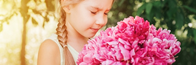 Ritratto di una bambina di sette anni caucasica carina e felice che tiene per mano e odora