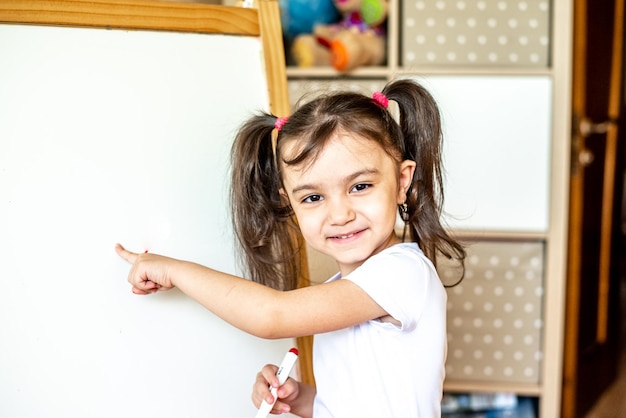 Ritratto di una bambina felice che scrive con un pennarello su una moderna lavagna intelligente durante le lezioni