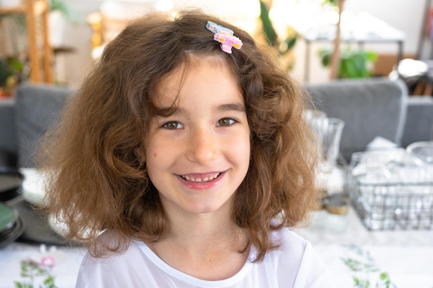 Ritratto di una bambina felice con un sorriso vivace e cattivo in primo piano con i capelli corti e ricci