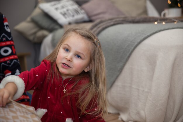 Ritratto di una bambina in abiti natalizi in camera da letto, il concetto del nuovo anno