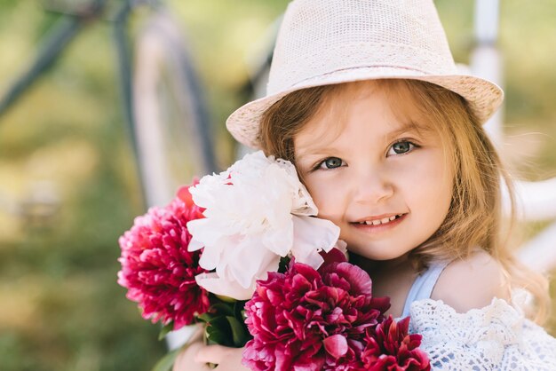 Ritratto di una bambina sorridente con un grande mazzo di fiori su backgroud verde te