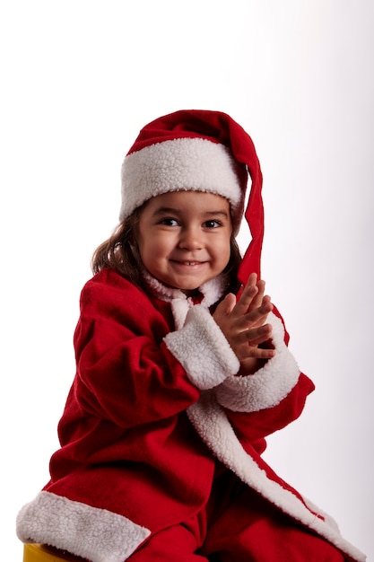 Ritratto di una bambina vestita da Babbo Natale con sfondo bianco