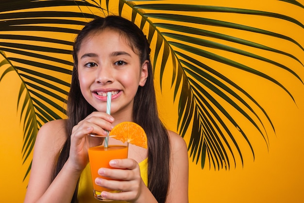 Ritratto di una bella bambina che gode di un succo d'arancia.