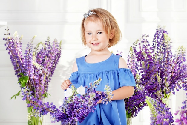 Ritratto di una bella bambina tra i fiori viola. Una decorazione floreale in un interno