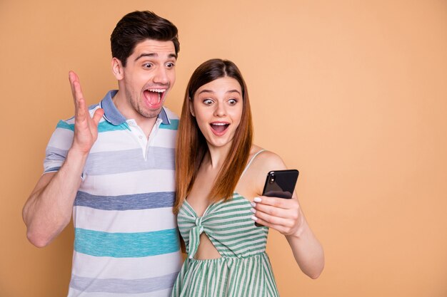 ritratto di una bella coppia pazza piuttosto stupita che legge grandi notizie telefoniche phone