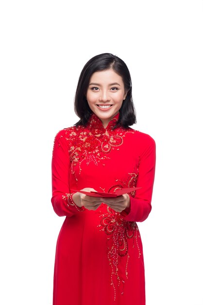 Ritratto di una bella donna asiatica in costume tradizionale del festival Ao Dai che tiene tasca rossa - soldi fortunati. Tet vacanza. Nuovo anno lunare.