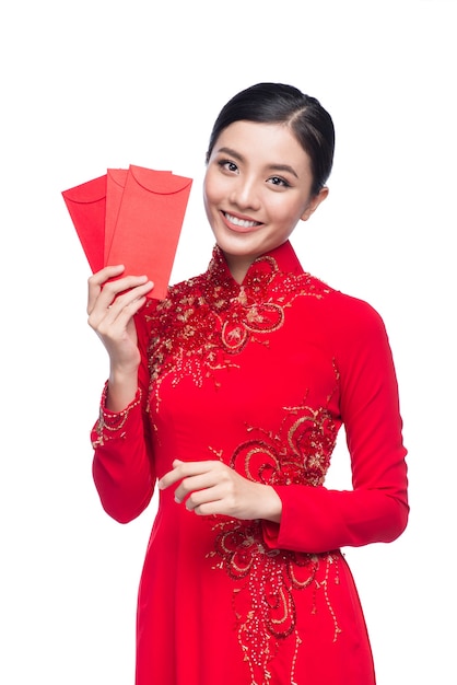 Ritratto di una bella donna asiatica in costume tradizionale del festival Ao Dai che tiene tasca rossa - soldi fortunati. Tet vacanza. Nuovo anno lunare.