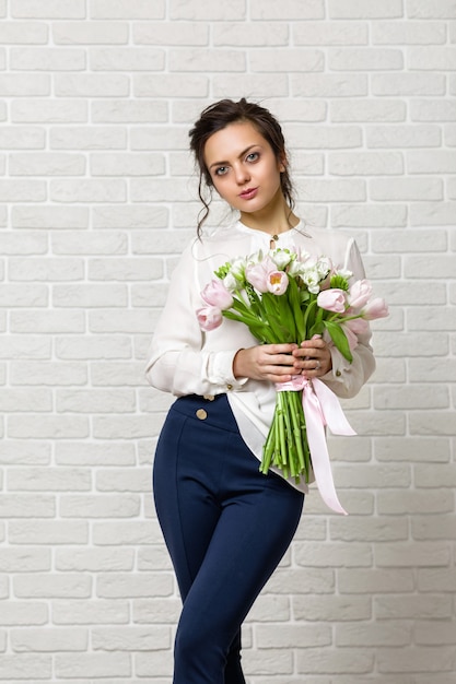 Ritratto di una bella donna bruna con un mazzo di fiori di tulipani